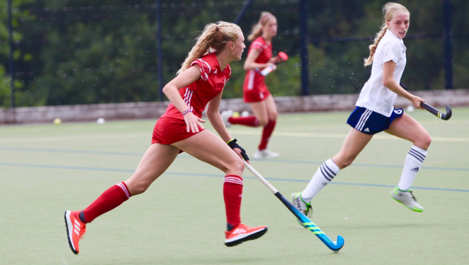 Three female hockey players running