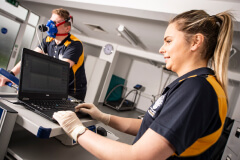 A student on a running machine while a second student looks at a laptop showing data on the first students performance