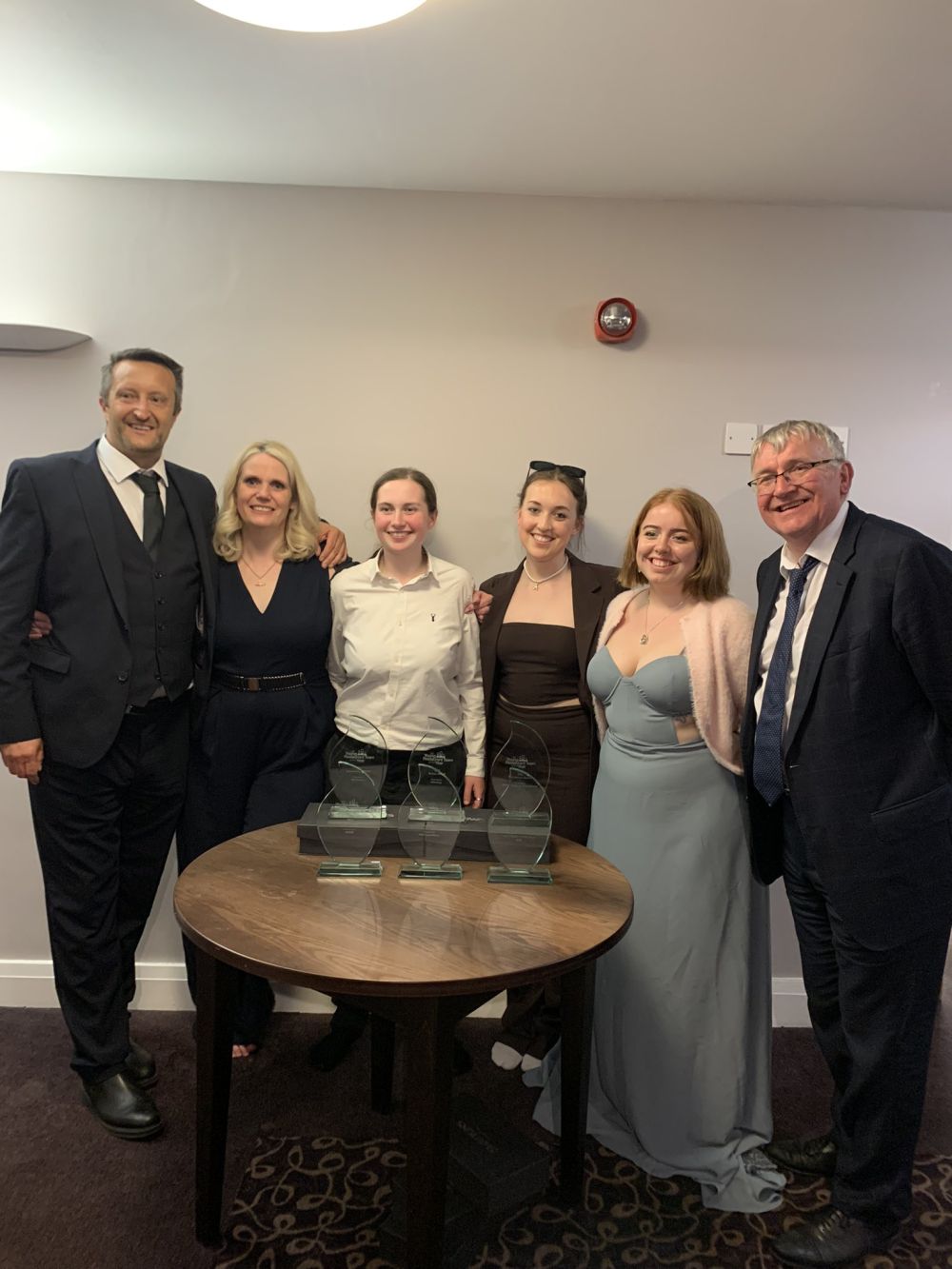 Loughborough college students standing in formal wear behing table with awards.