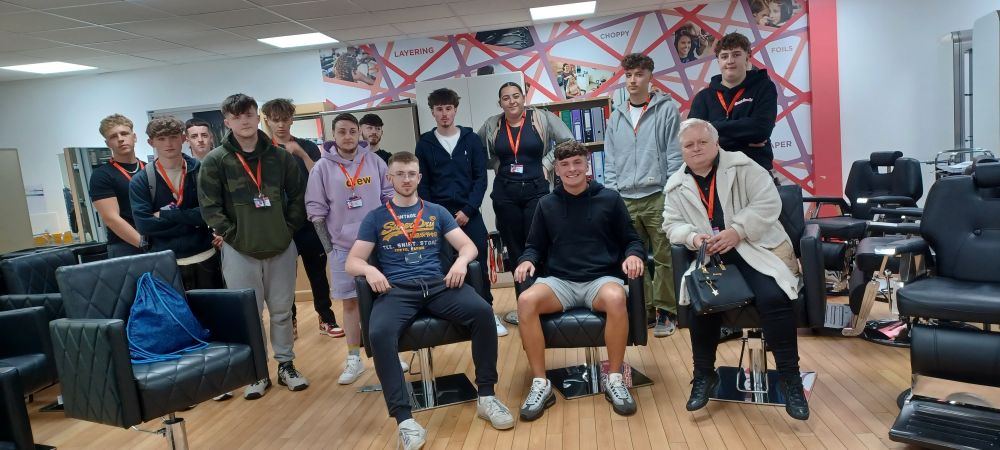 Alumni George sits with current barbering students