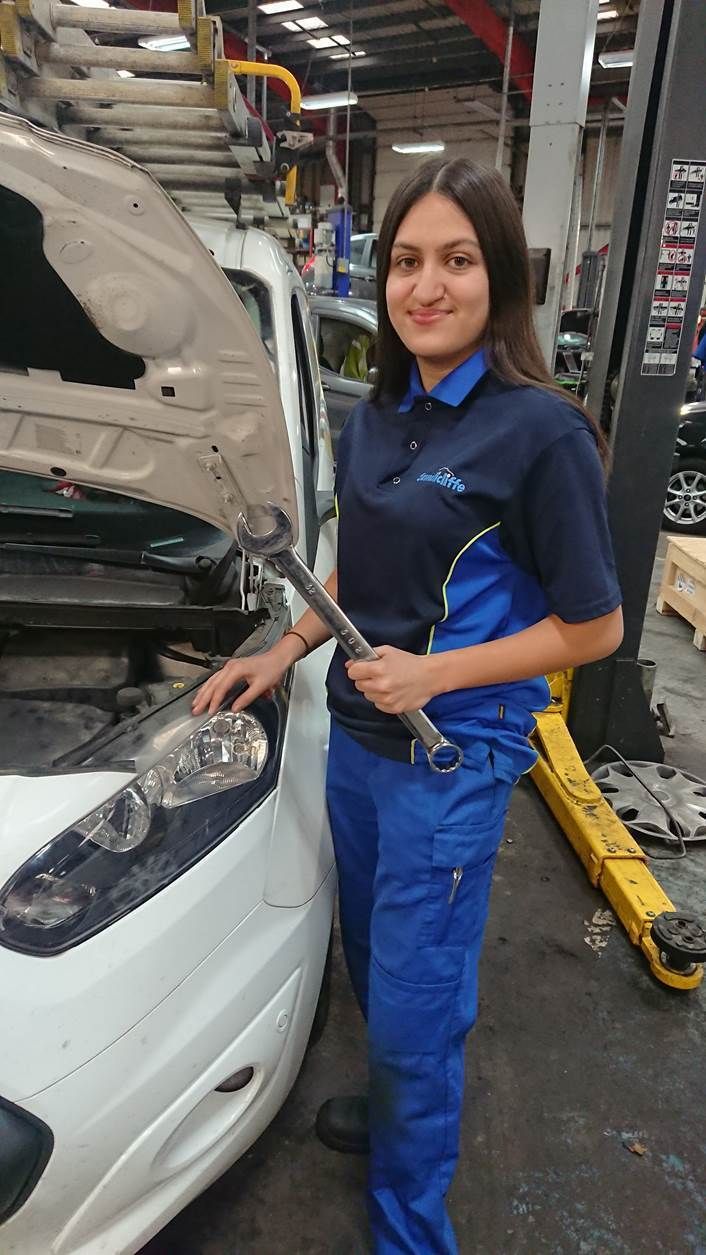 Student mechanic Kinnari Khodiara standing next to a car with its bonnet open holding a spanner