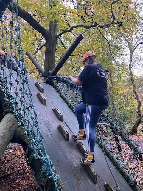  Level 2 Childcare student climbing up a steep climbing wall slope attached to a harness