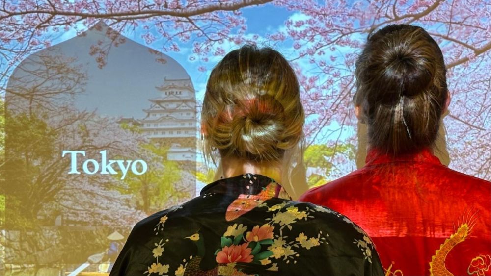 Two women face away from the camera, they are wearing kimonos