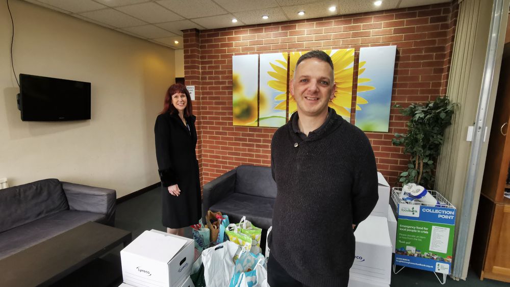 Anne-Marie Francis, Vice Principal at the College and Jules Ibbitt, the Loughborough Area Foodbank Manager for the Trussell Trust standing in a room with dontated items including food, toiletries and gift items